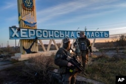 Two members of the Ukrainian defense forces stand next to a sign reading 'Kherson region' on the outskirts of Kherson on November 14, 2022. (Bernat Armangue/AP)