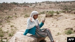 A woman tries to reach mobile phone signal after most of an area went out of power in Samre, southwest of Mekele in Tigray region, Ethiopia, June 20, 2021. ( Yasuyoshi Chiba/AFP)