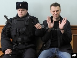 Russian opposition leader Alexey Navalny, right, poses for the press as he sits handcuffed in court in Moscow on March 30, 2017. (AP)