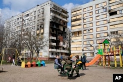 Children play in a playground in front of missile-damaged buildings ahead of a visit by Ukraine's President Volodymyr Zelenskyy in Zaporizhzhia on March 27, 2023. (Efrem Lukatsky/AP)