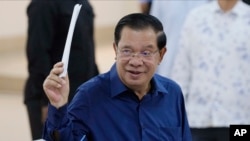 Cambodian Prime Minister Hun Sen of the Cambodian People's Party (CPP) raises a ballot before voting at a polling station at Takhmua in Kandal province on July 23, 2023. (Heng Sinith/AP) 