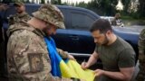 Ukraine's President Volodymyr Zelenskyy signs a national flag for a service member at a petrol station after visiting positions near the front line in Donetsk region on June 26, 2023. (Ukrainian Presidential Press Service/via Reuters)