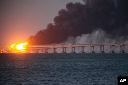 Flame and smoke rise from the Kerch Bridge connecting the Russian mainland and Ukraine's Crimean Peninsula on October 8, 2022. (AP)
