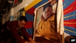 A Tibetan living in Taiwan places candles in front of the portrait of the Dalai Lama during a candlelight vigil at Liberty Square in Taipei on March 10, 2023, to mark the 64th anniversary of the failed 1959 Tibetan uprising against Chinese rule. (Chiang Ying-ying/AP)