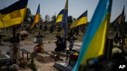 A woman cries at the grave of her son, who died fighting in the war, as Ukrainians mark Independence Day in Kharkiv, on August 24, 2023. (Bram Janssen/AP)