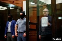 Former U.S. Marine Paul Whelan, who was detained and accused of espionage, holds a sign as he stands inside a defendants' cage during his verdict hearing in Moscow, Russia June 15, 2020. (REUTERS/Maxim Shemetov)