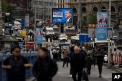 People walk by a billboard showing Turkish President and People's Alliance's presidential candidate Recep Tayyip Erdogan, in Istanbul, on April 27, 2023. (Khalil Hamra/AP)