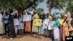 Parents of abducted Chibok girls hold photographs of their daughters during a commemoration at the Chibok Local Government on April 14, 2019, five years after they were abducted by Boko Haram.
