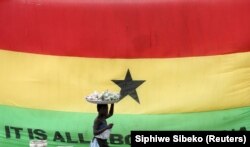 A girl walks past a flag of Ghana outside the Cape Coast Castle, in Ghana, July 28, 2019. (Siphiwe Sibeko/Reuters)