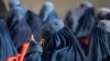 Afghan burqa-clad women sit as they wait to receive cash money being distributed as an aid by the World Food Programme organisation in Pul-i-Alam, the provincial capital of Logar Province on January 7, 2024. (Wakil KOHSAR / AFP)