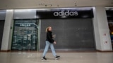 A woman walking past a closed Adidas store in Chekov, near Moscow, on May 27, 2022. (Photo by Yuri KADOBNOV / AFP)