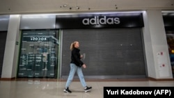 A woman walking past a closed Adidas store in Chekov, near Moscow, on May 27, 2022. (Photo by Yuri KADOBNOV / AFP)