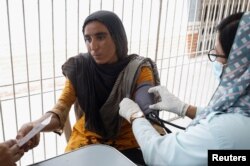 Saima, 23, displaced because of the floods, receives medical assistance while taking refuge in a school in Karachi on September 22, 2022. (Akhtar Soomro/Reuters)