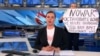 This video grab taken on March 15, 2022, shows Russian Channel One editor Marina Ovsyannikova holding a poster that reads "Stop the war. Don't believe the propaganda. Here, they are lying to you." (AFP)