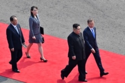 North Korea's leader Kim Jong Un (2nd R) walks with South Korea's President Moon Jae-in (R), followed by Kim's sister and close adviser Kim Yo Jong (2nd L), down a red carpet to the official summit Peace House building for their meeting at Panmunjom on Ap