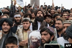 A Taliban fighter holds a poster of late Afghan leader of the Haqqani network Jalaluddin Haqqani, while chanting victory slogans at the Ahmad Shah Massoud Square near the US embassy in Kabul on August 15, 2022. (Wakil Kohsar/AFP)