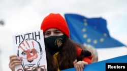 A young woman holds a drawing of Russian President Vladimir Putin during a protest against Russia's invasion of Ukraine in Niksic, Montenegro, on March 6, 2022.