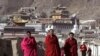 Tibetan Buddhist monks walk with a backdrop of the Labrang Monastery in Xiahe, Gansu Province, on March 16, 2008. The previous day, police fired tear gas to disperse hundreds of Buddhist monks and other Tibetans after they marched from the monastery. (Andy Wong/AP)