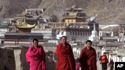 Tibetan Buddhist monks walk with a backdrop of the Labrang Monastery in Xiahe, Gansu Province, on March 16, 2008. The previous day, police fired tear gas to disperse hundreds of Buddhist monks and other Tibetans after they marched from the monastery. (Andy Wong/AP)