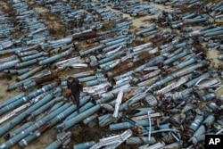 A war prosecutor observes collected parts of Russian rockets which were used to attack the city of Kharkiv on December 22, 2022. (Evgeniy Maloletka/AP)