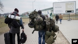 A man carries combat gear as he leaves Poland to fight in Ukraine, at the border crossing in Medyka, Poland, Wednesday, March 2, 2022. (AP Photo/Markus Schreiber, File)