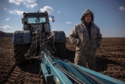 A Ukrainian farmer takes a break from ploughing a field near the village of Yakovlivka, outside of Kharkiv, after it was hit by an aerial bombardment on April 5, 2022. (Thomas Peter/Reuters)
