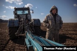 A Ukrainian farmer takes a break from ploughing a field near the village of Yakovlivka, outside of Kharkiv, after it was hit by an aerial bombardment on April 5, 2022. (Thomas Peter/Reuters)