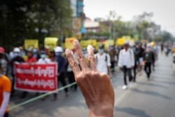 Anti-coup protesters gesture with a three-fingers salute, a symbol of resistance, as they demonstrate against the military coup in Mandalay on March 15, 2021.