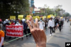 Manifestantes antigolpistas saludan con tres dedos, símbolo de resistencia, mientras se manifiestan contra el golpe militar en Mandalay el 15 de marzo de 2021.