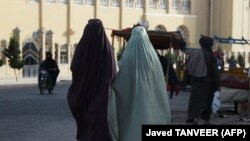 Burqa-clad women walk along a street one day after the Taliban ordered women to cover fully in public, Kandahar, May 7, 2022. (Javed Tanveer/AFP)