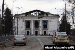 People walk past the Donetsk Academic Regional Drama Theater in Mariupol after a March 16, 2022, Russian airstrike on the building, which was being used as a bomb shelter. (Alexei Alexandro/Associated Press)