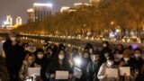 People in Beijing gather for a vigil and hold white sheets of paper on November 27, 2022, in protest over COVID-19 restrictions. (Thomas Peter/Reuters) 