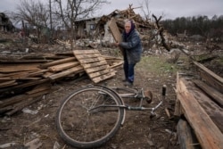 A woman collects wooden planks in a street destroyed by shellings in Chernihiv, on Wednesday, April 13, 2022. (Evgeniy Maloletka/AP)