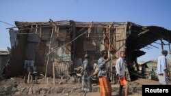 Residents and militias stand next to houses destroyed by an airstrike during fighting between the Ethiopian National Defence Forces (ENDF) and the Tigray People's Liberation Front (TPLF) forces in Kasagita town, Afar region, on February 25, 2022. (Tiksa Negeri/Reuters)