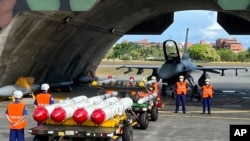 Military personnel stand next to U.S. Harpoon A-84, anti-ship missiles and AIM-120 and AIM-9 air-to-air missiles prepared for a weapon loading drills in front of a U.S. F-16V fighter jet at the Hualien Airbase in Taiwan's southeastern Hualien county, Aug.17, 2022.(AP/Johnson Lai)