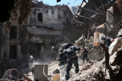 Emergency workers from the unrecognized Donetsk People's Republic clear rubble at the bombed out Mariupol theater on May 12, 2022. (Associated Press)
