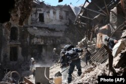 Workers from the self-proclaimed Donetsk People's Republic Emergency Situations Ministry clear rubble near the damaged Mariupol theater building on May 12, 2022. (Associated Press)