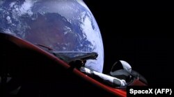 Space -- This still image taken from a SpaceX livestream video shows "Starman" sitting in SpaceX CEO Elon Musk's cherry red Tesla roadster after the Falcon Heavy rocket delivered it into orbit around the Earth on 6Feb2018.