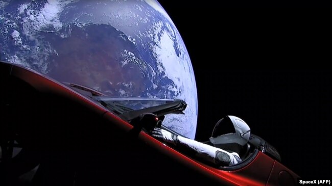 Space -- This still image taken from a SpaceX livestream video shows "Starman" sitting in SpaceX CEO Elon Musk's cherry red Tesla roadster after the Falcon Heavy rocket delivered it into orbit around the Earth on 6Feb2018.