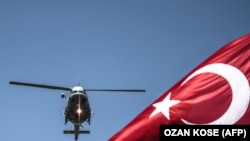 Turkish army helicopter flies behind a Turkish flag during a military parade marking the 93rd anniversary of Victory Day in Istanbul on August 30, 2015.