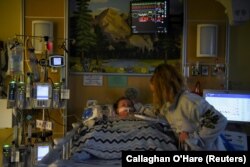 Tiffany Jackson comforts her son Adrian James, 2, who tested positive for the coronavirus disease (COVID-19), as he breathes with assistance from a ventilator at SSM Health Cardinal Glennon Children's Hospital in St. Louis, Missouri, on October 5, 2021.
