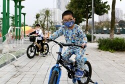 VIETNAM -- Children wearing a face mask as a preventive measure against the spread of COVID-19 novel coronavirus ride their bicycles in Hanoi on March 20, 2020.