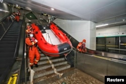 Rescue workers enter a subway station of Metro Line 5 to inspect the floodwaters following heavy rainfall in Zhengzhou, Henan province, China July 26, 2021. (China Daily via Reuters)