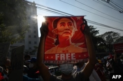 Un manifestante sostiene un cartel que muestra a Aung San Suu Kyi durante una manifestación contra el golpe militar frente al Banco Central de Myanmar en Yangon, el 15 de febrero de 2021 (AFP)