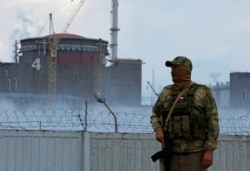 A serviceman with a Russian flag on his uniform stands guard near the Zaporizhzhia Nuclear Power Plant. (Reuters)