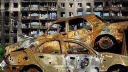 Burned cars are pictured in front of a destroyed building in the city of Mariupol on July 1, 2022, amid the ongoing Russian military action in Ukraine. (AFP)