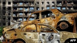 Burned cars are pictured in front of a destroyed building in the city of Mariupol on July 1, 2022, amid the ongoing Russian military action in Ukraine. (AFP)
