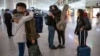 Expelled Wall Street Journal reporters, from right, Stephanie Yang, Julie Wernau, and Stu Woo embrace embrace colleagues before their departure at Beijing Capital International Airport March 28, 2020. (Mark Schiefelbein/AP)