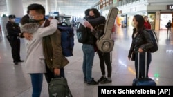 Expelled Wall Street Journal reporters, from right, Stephanie Yang, Julie Wernau, and Stu Woo embrace embrace colleagues before their departure at Beijing Capital International Airport March 28, 2020. (Mark Schiefelbein/AP)