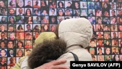 Relatives react in front of a huge screen bearing portraits of late crew members and passengers of Ukraine International Airlines Flight PS752 during a commemorative ceremony in Ukraine's capital Kiev, January 8, 2021. (Genya Savilov/AFP)